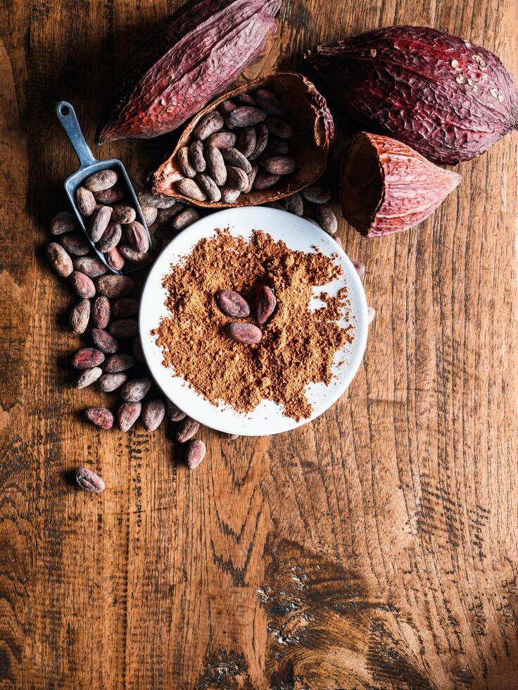 Top view of Natural cocoa powder with brown cocoa beans and dry cacao pod on a vintage wooden table. photo