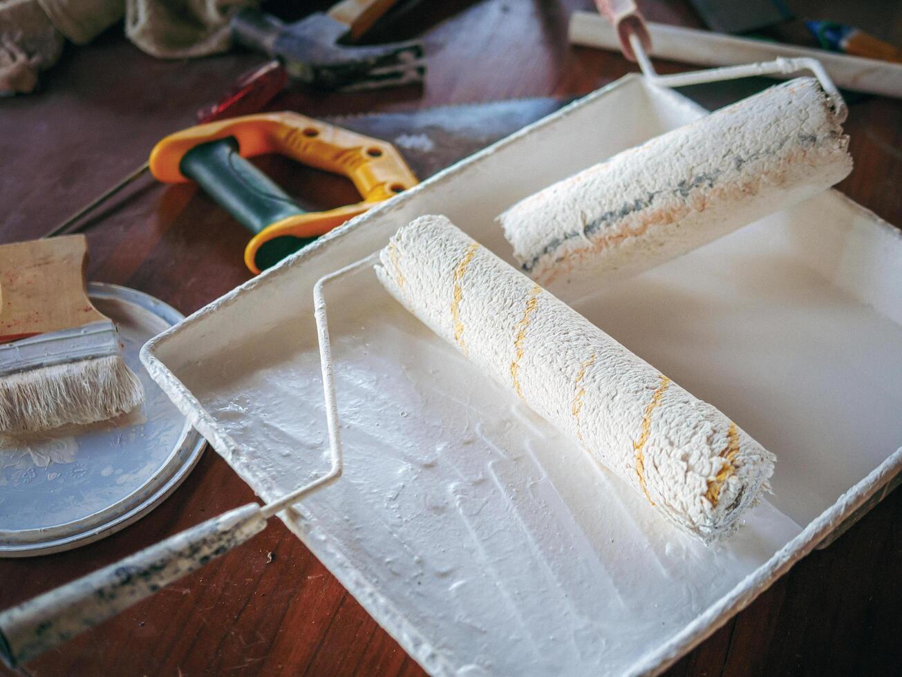 Professional home decorator and painter worker tools rollers and brushes for painting on a white wooden background.Top view photo