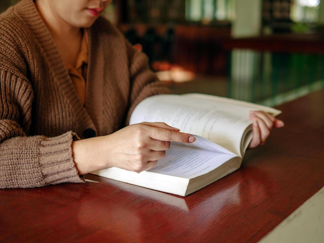 Learning, education Hand of asian woman sitting reading fiction book on wooden table in the morning,relax and enjoy books. photo