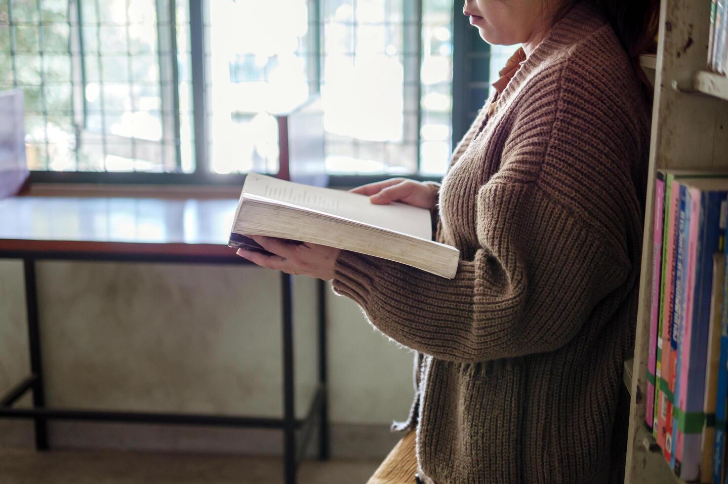 Learning, education Hand of Senior woman standing holding a book in library by the window in the morning, relax and enjoy books. photo