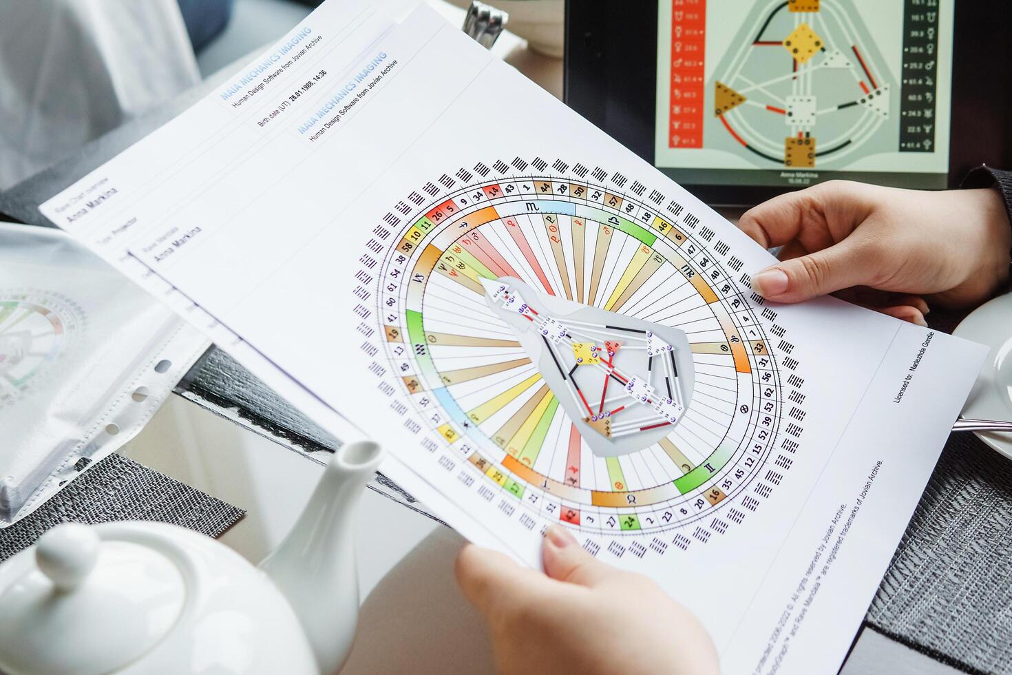 TVER, RUSSIA - FEBRUARY 12, 2023. A woman at the table is studying a rave mandala by human design. Rave mandala on the table close-up. The concept of esoteric teachings. photo