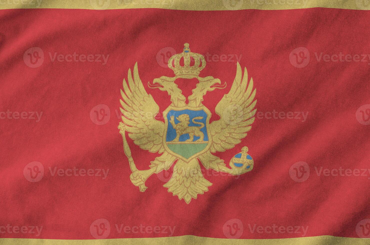 Montenegro flag depicted on folded wavy fabric of old cloth photo