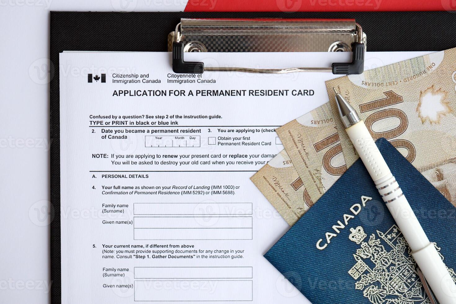 Application for permanent resident card on table with pen and canadian passport with money photo