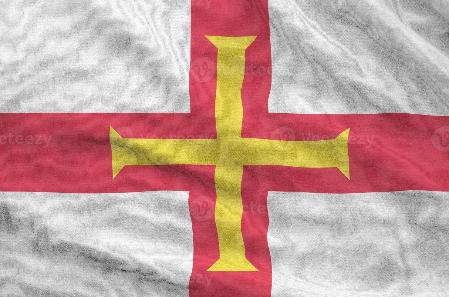 Guernsey flag depicted on folded wavy fabric of old cloth photo