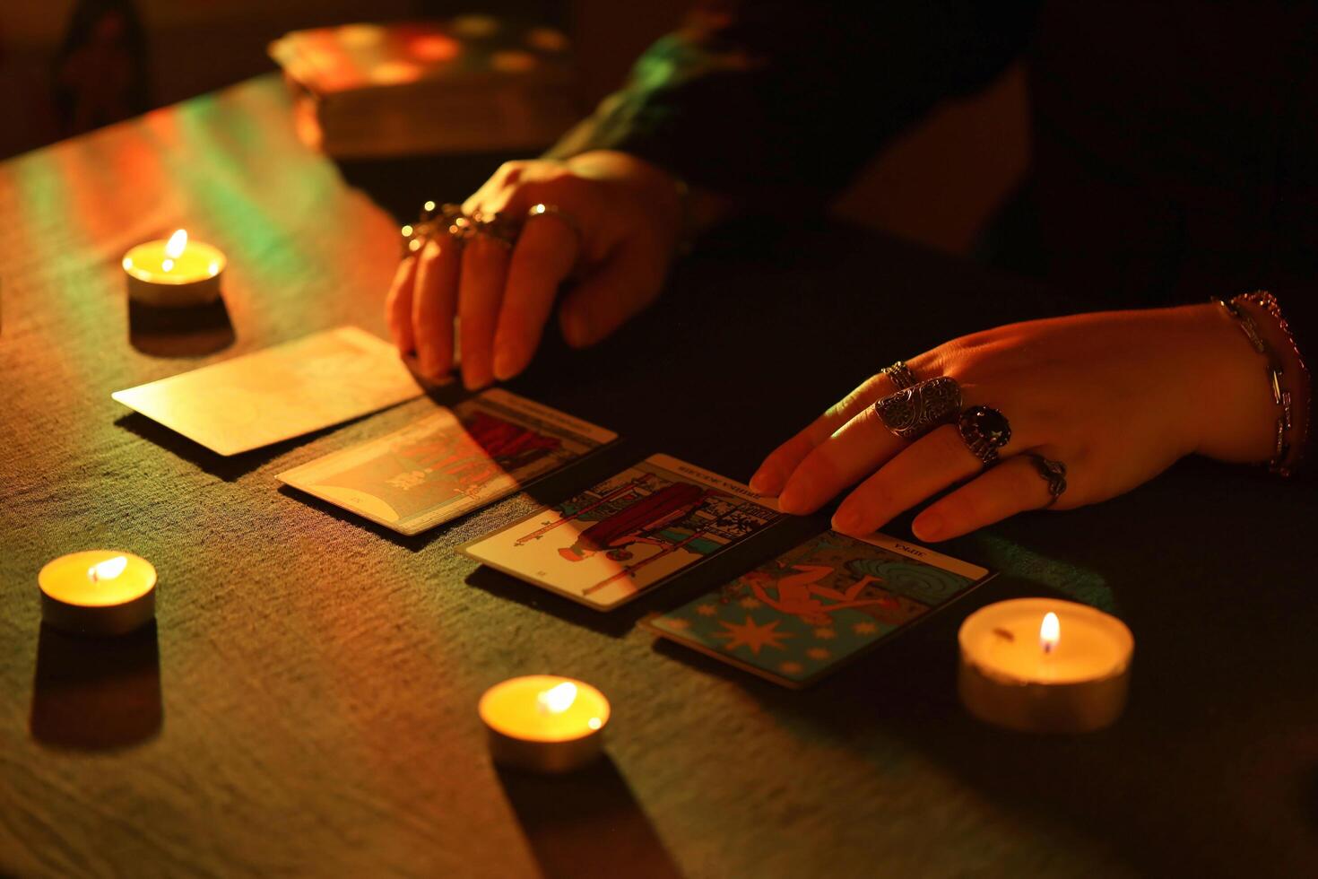 KYIV, UKRAINE - JULY 10, 2024 Tarot reader picking tarot cards. Candlelight in dark room. Tarot reader or fortune teller reading and forecasting photo