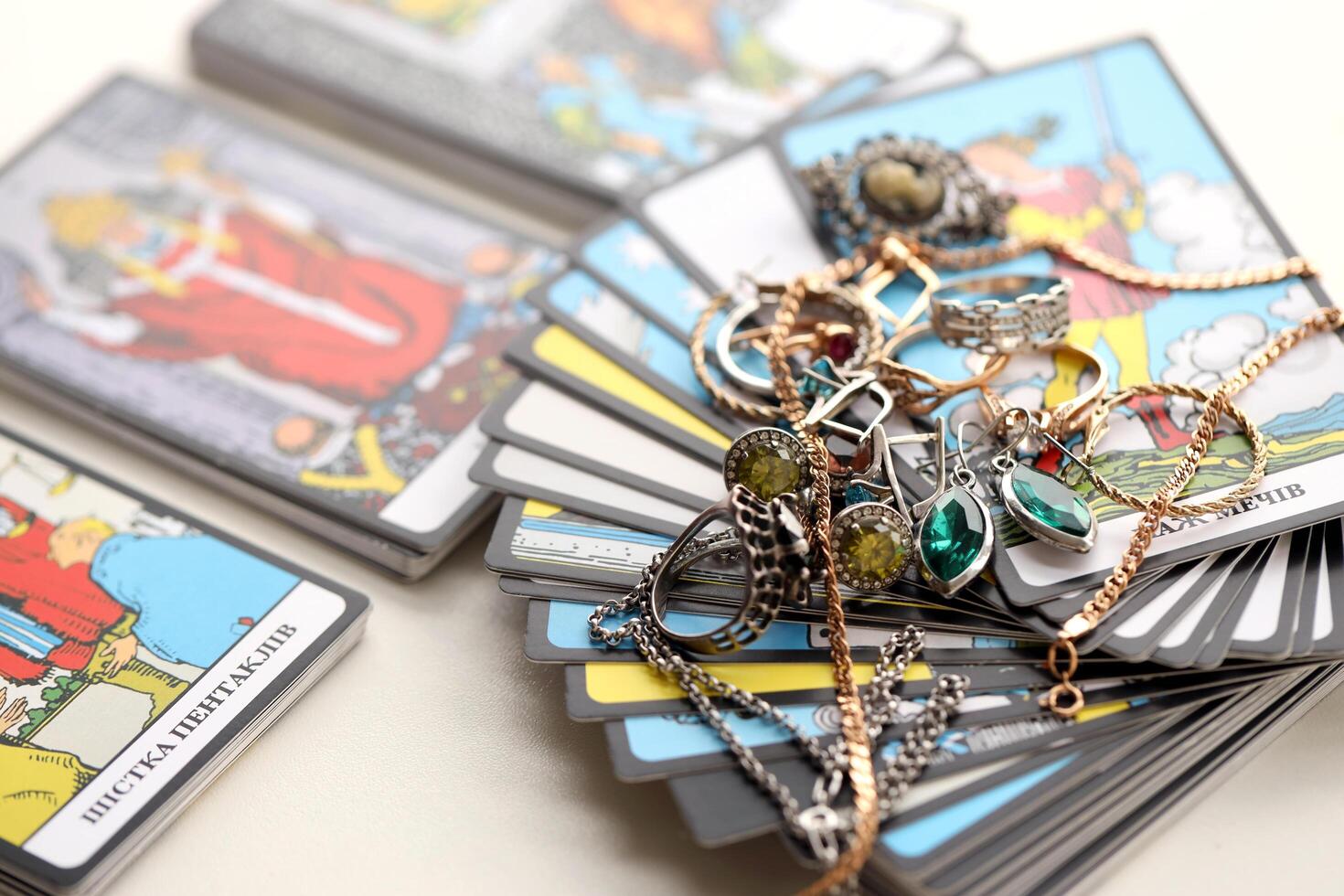 KYIV, UKRAINE - JULY 10, 2024 Tarot minor and major arcana cards of Rider Waite esoteric deck and golden rings and necklace chains. Many tarot cards for fortune telling and expensive items photo