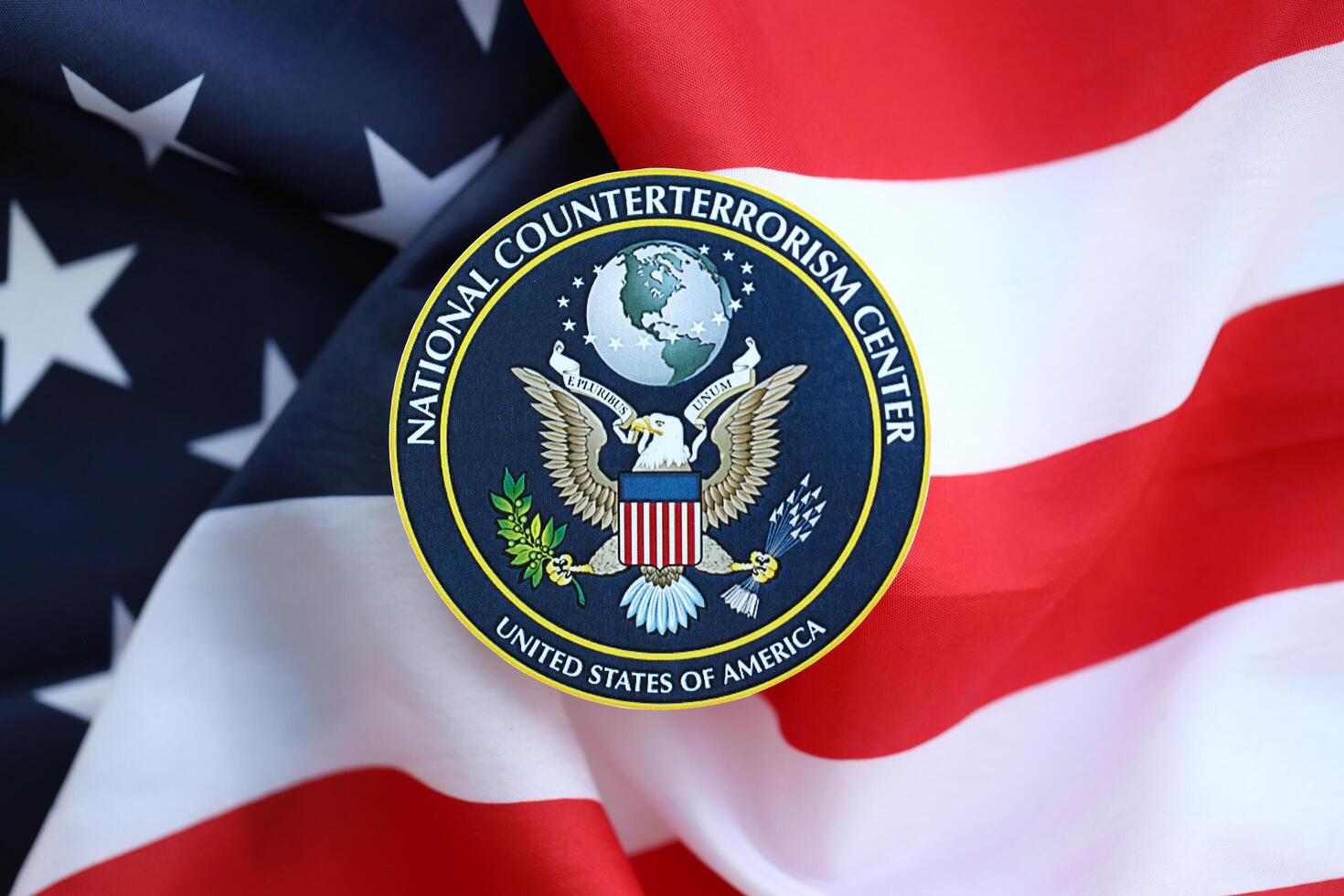 KYIV, UKRAINE - JUNE 26, 2024 United States National Counterterrorism Center coat of arms sticker on folded US flag photo
