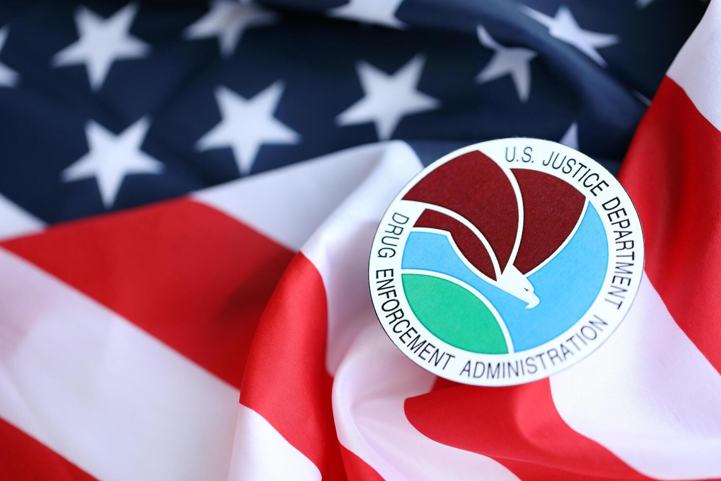 KYIV, UKRAINE - JUNE 26, 2024 U.S. Justice Department Drug Enforcement Administration coat of arms sticker on folded US flag photo