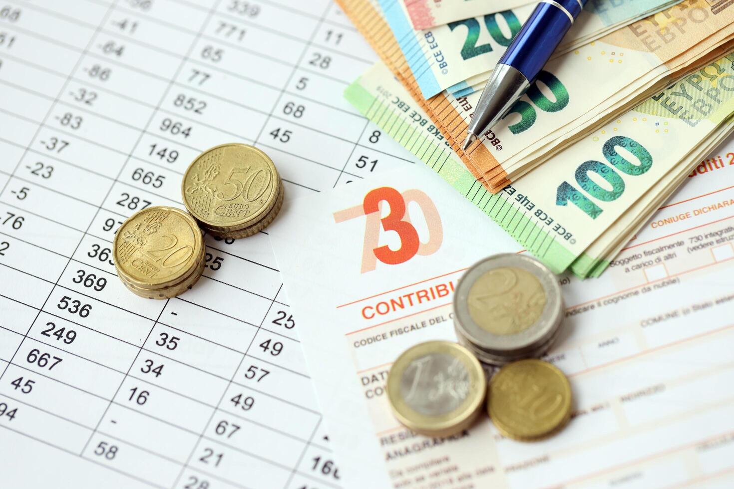 KYIV, UKRAINE - APRIL 20, 2024 many euro banknotes with the Modello 730 tax form as background, translating in Italian as declaration of incomes photo