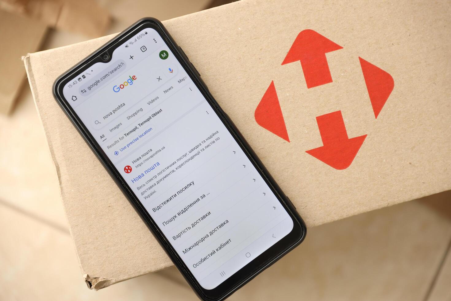 KYIV, UKRAINE - APRIL 20, 2024 Nova Poshta Logotype on cardboard box and website on smartphone screen. Nova Poshta is best ukrainian postal service company photo