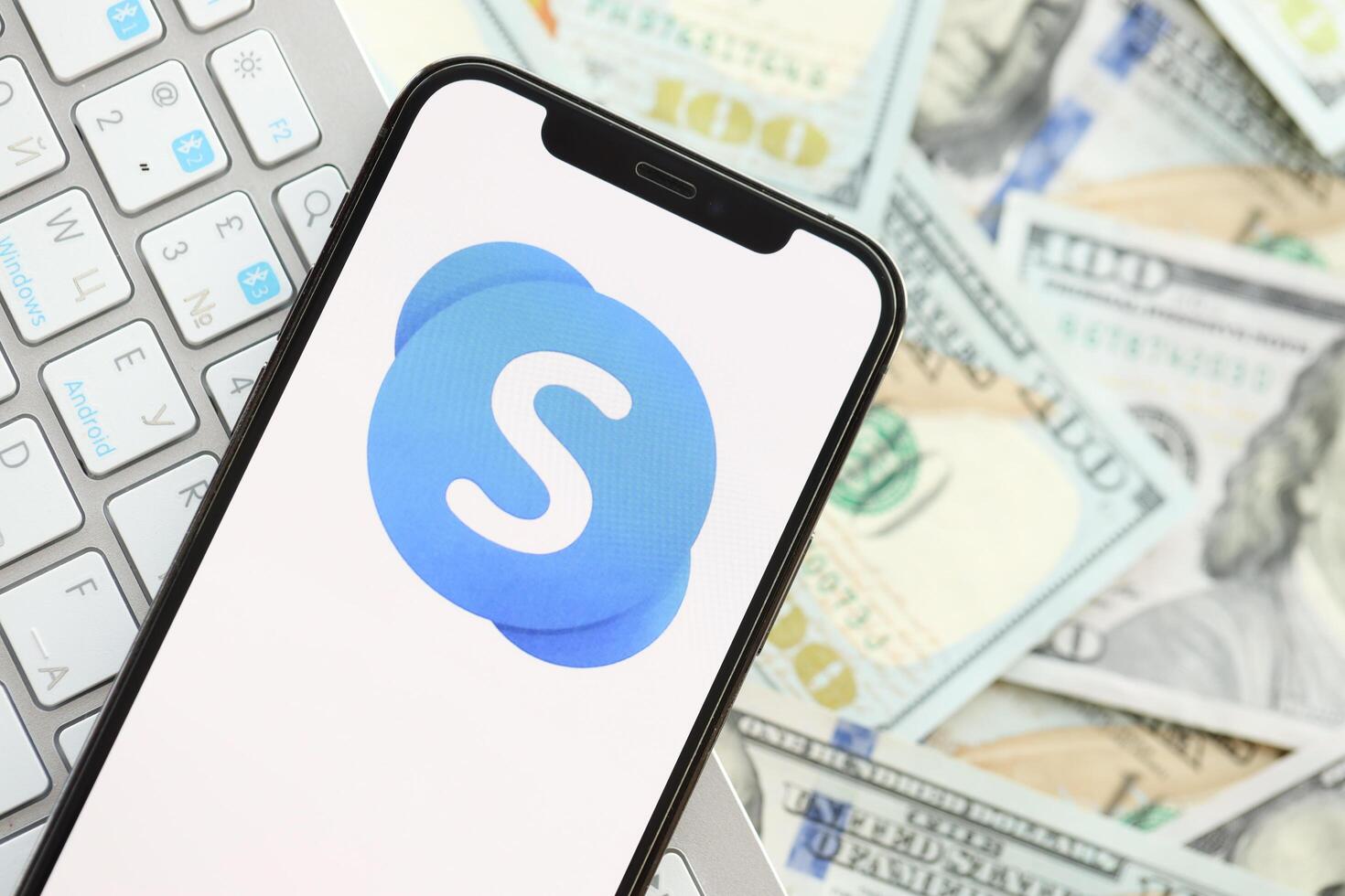 KYIV, UKRAINE - APRIL 1, 2024 Skype icon on smartphone screen on many usd money bills photo