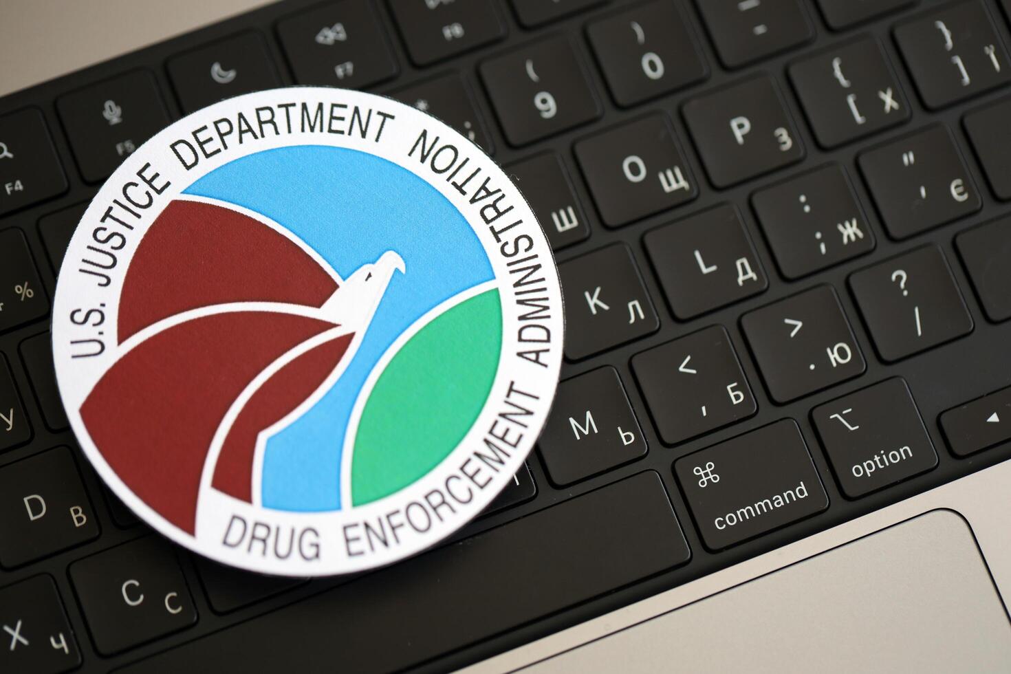 KYIV, UKRAINE - JUNE 26, 2024 U.S. Justice Department Drug Enforcement Administration coat of arms sticker on silver laptop photo