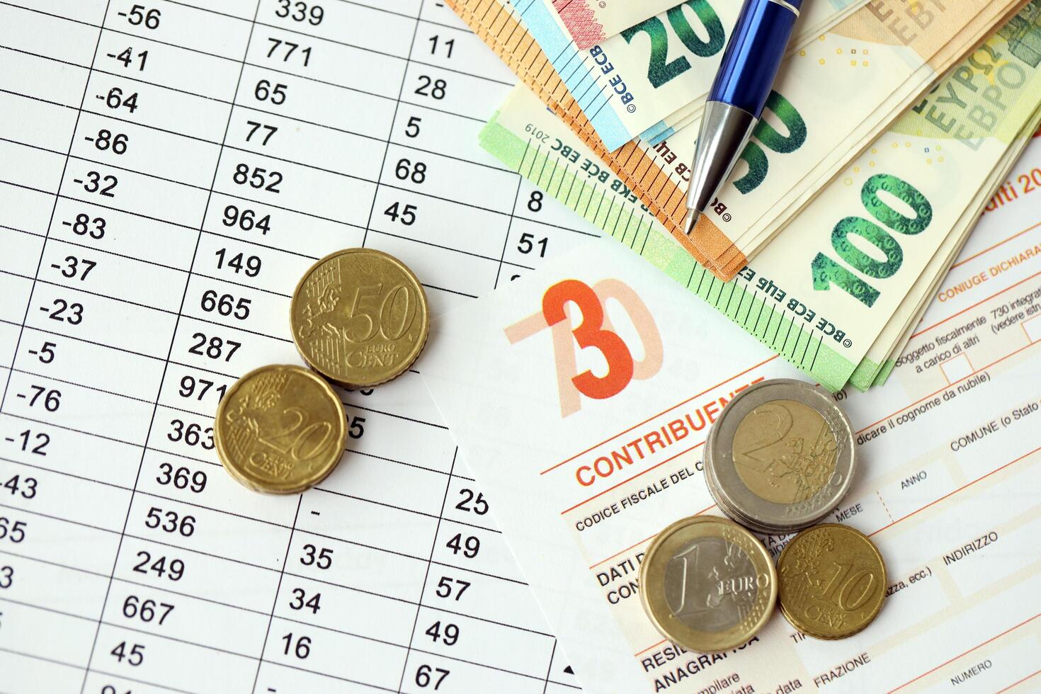 KYIV, UKRAINE - APRIL 20, 2024 many euro banknotes with the Modello 730 tax form as background, translating in Italian as declaration of incomes photo