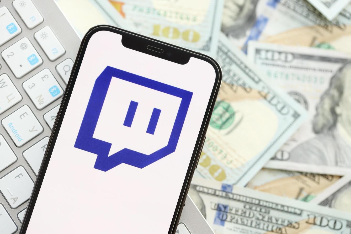 KYIV, UKRAINE - APRIL 1, 2024 Twitch icon on smartphone screen on many usd money bills photo