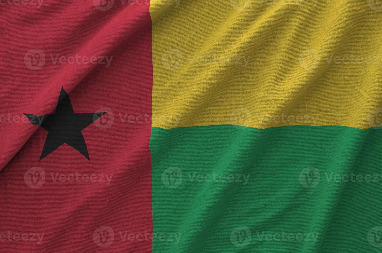 Guinea Bissau flag depicted on folded wavy fabric of old cloth photo