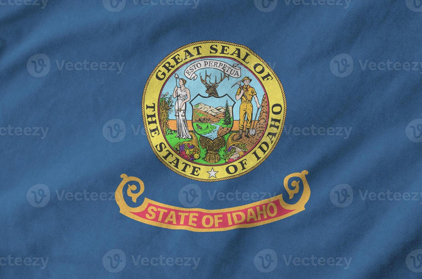 Idaho US state flag depicted on folded wavy fabric of old cloth photo