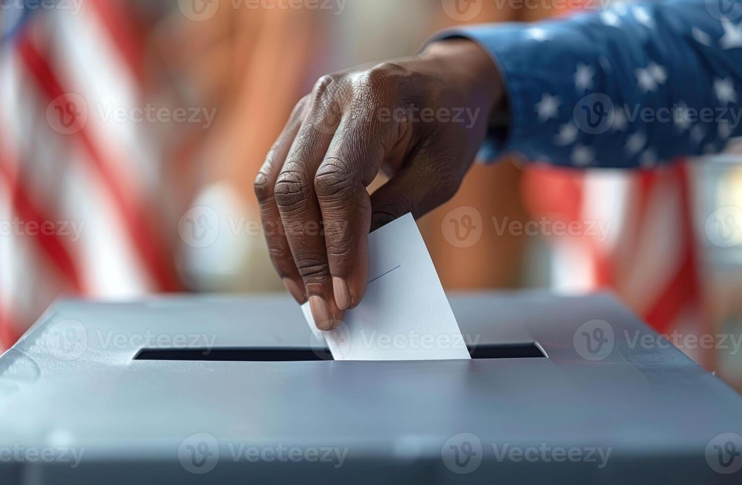 Hand placing a ballot into a box with American flags in the background, symbolizing voting photo