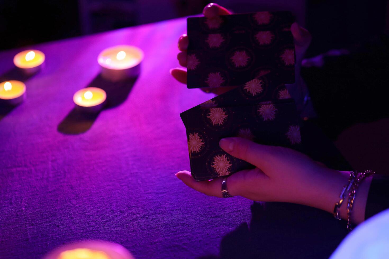 KYIV, UKRAINE - JULY 10, 2024 Tarot reader picking tarot cards. Candlelight in dark room. Tarot reader or fortune teller reading and forecasting photo