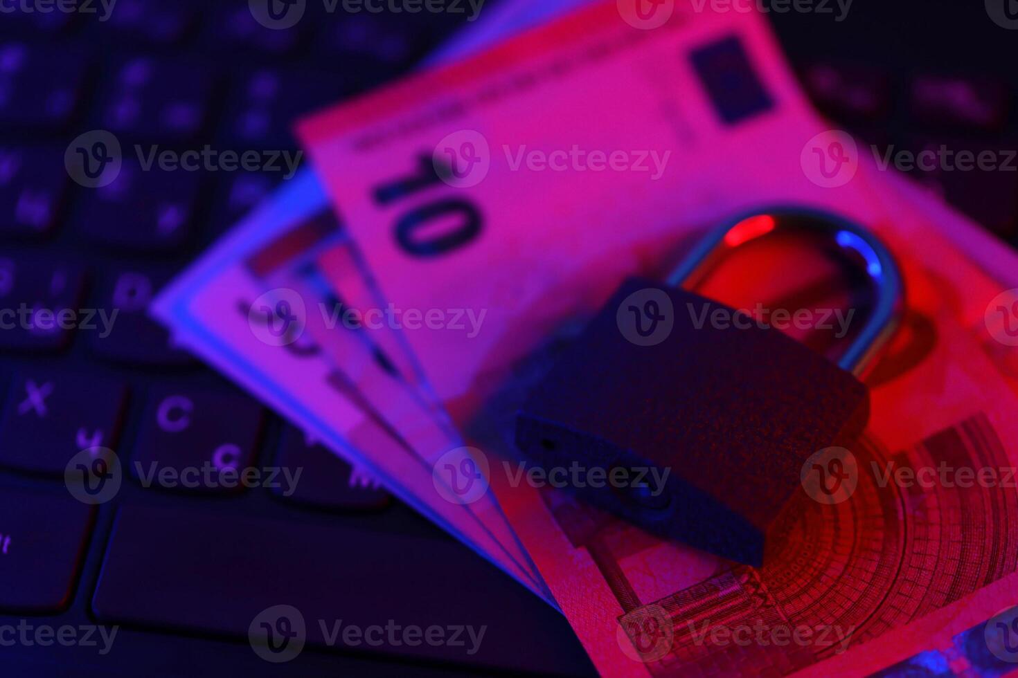 Closed padlock with euro money bills on laptop keyboard close up. Safe online banking or online shopping concept photo