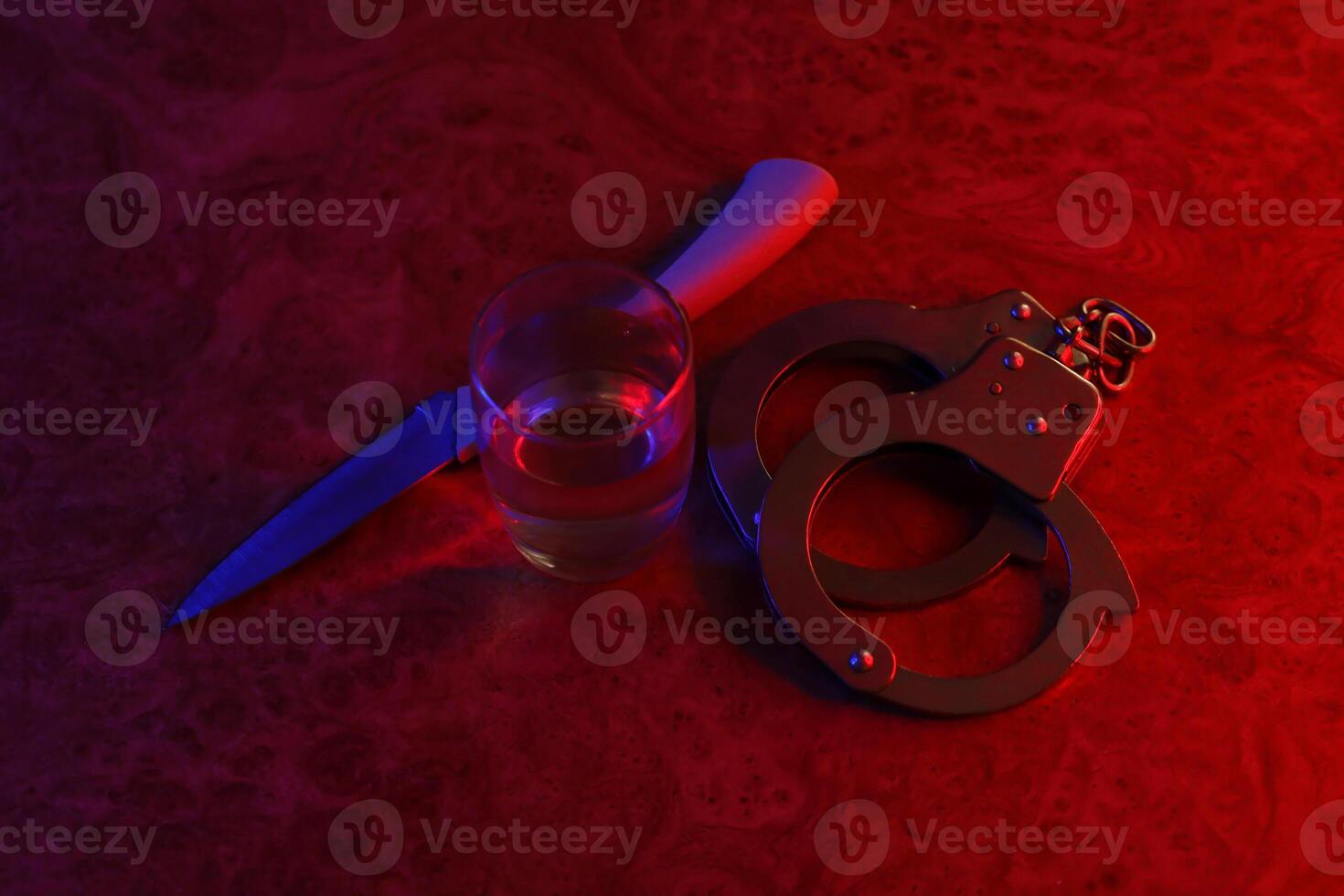 Glass with vodka alcohol drink, knife and handcuffs. Concept of alcoholism, criminal photo