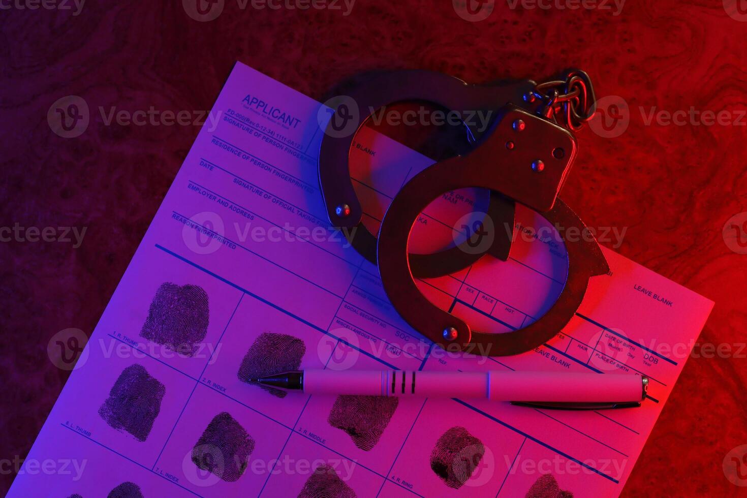 Applicant or fingerprints card with police handcuffs on table in dark room photo