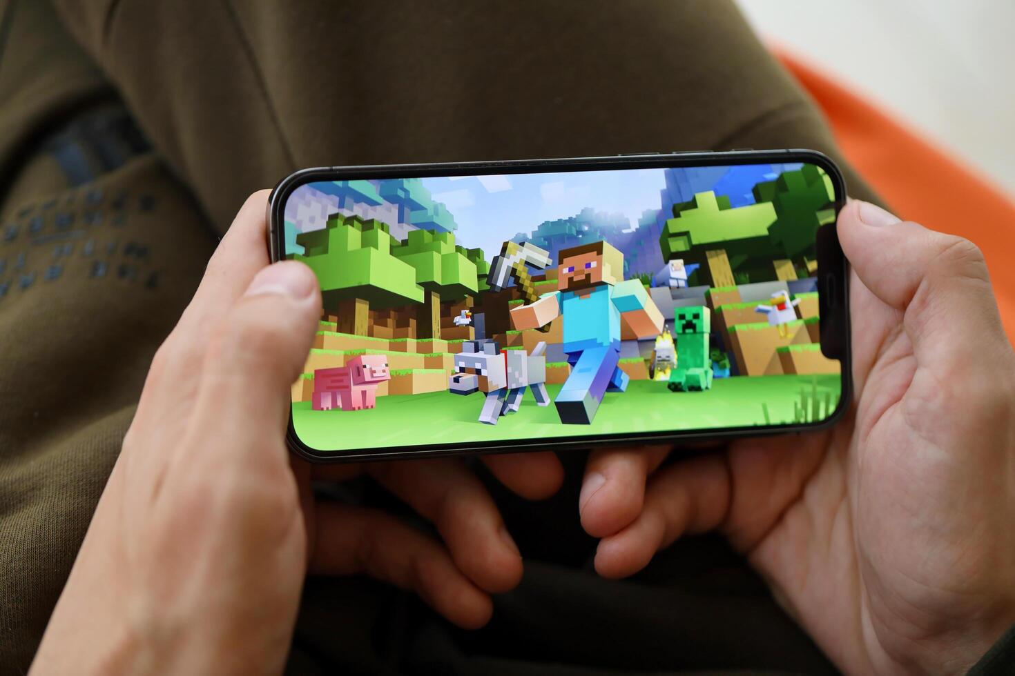Minecraft mobile iOS game on iPhone 15 smartphone screen in male hands during mobile gameplay photo
