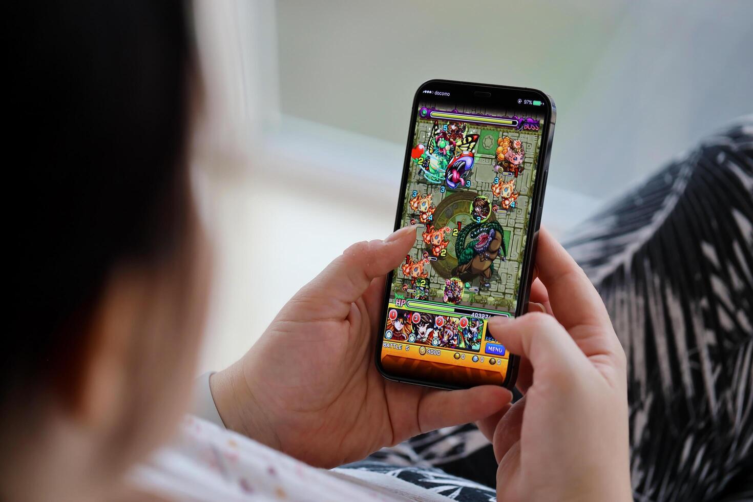 Monster Strike mobile iOS game on iPhone 15 smartphone screen in female hands during mobile gameplay photo