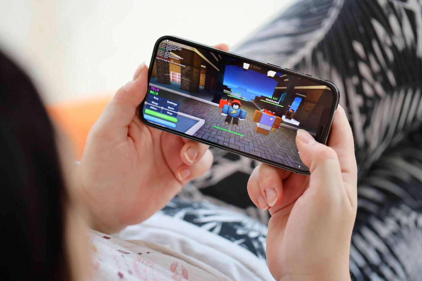 Roblox mobile iOS game on iPhone 15 smartphone screen in female hands during mobile gameplay photo