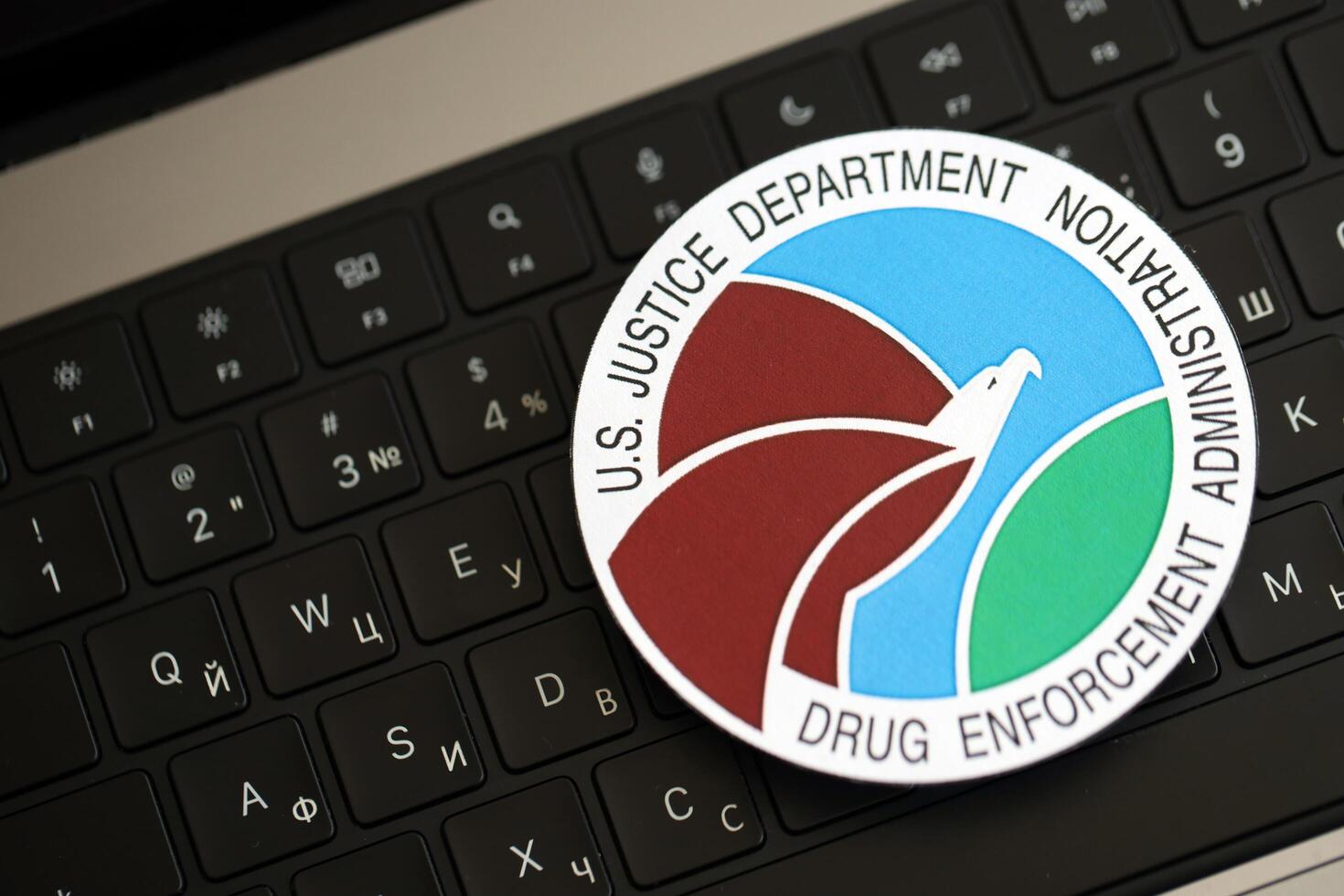 KYIV, UKRAINE - JUNE 26, 2024 U.S. Justice Department Drug Enforcement Administration coat of arms sticker on silver laptop photo
