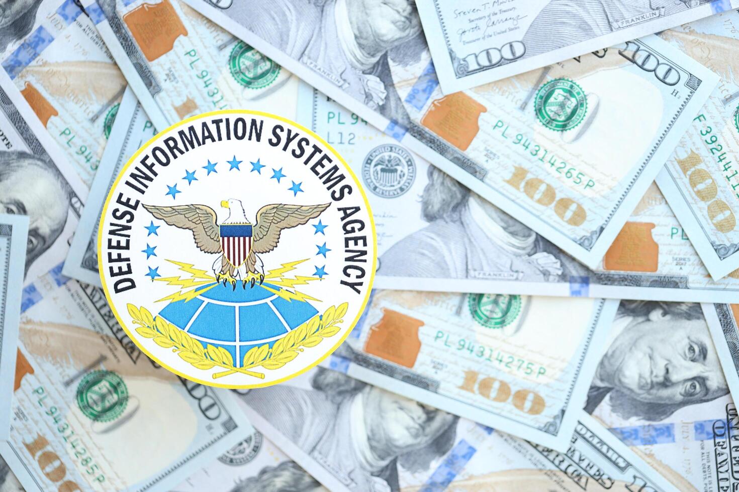 KYIV, UKRAINE - JUNE 26, 2024 Defense Information Systems Agency coat of arms on big amount of US dollar banknotes photo
