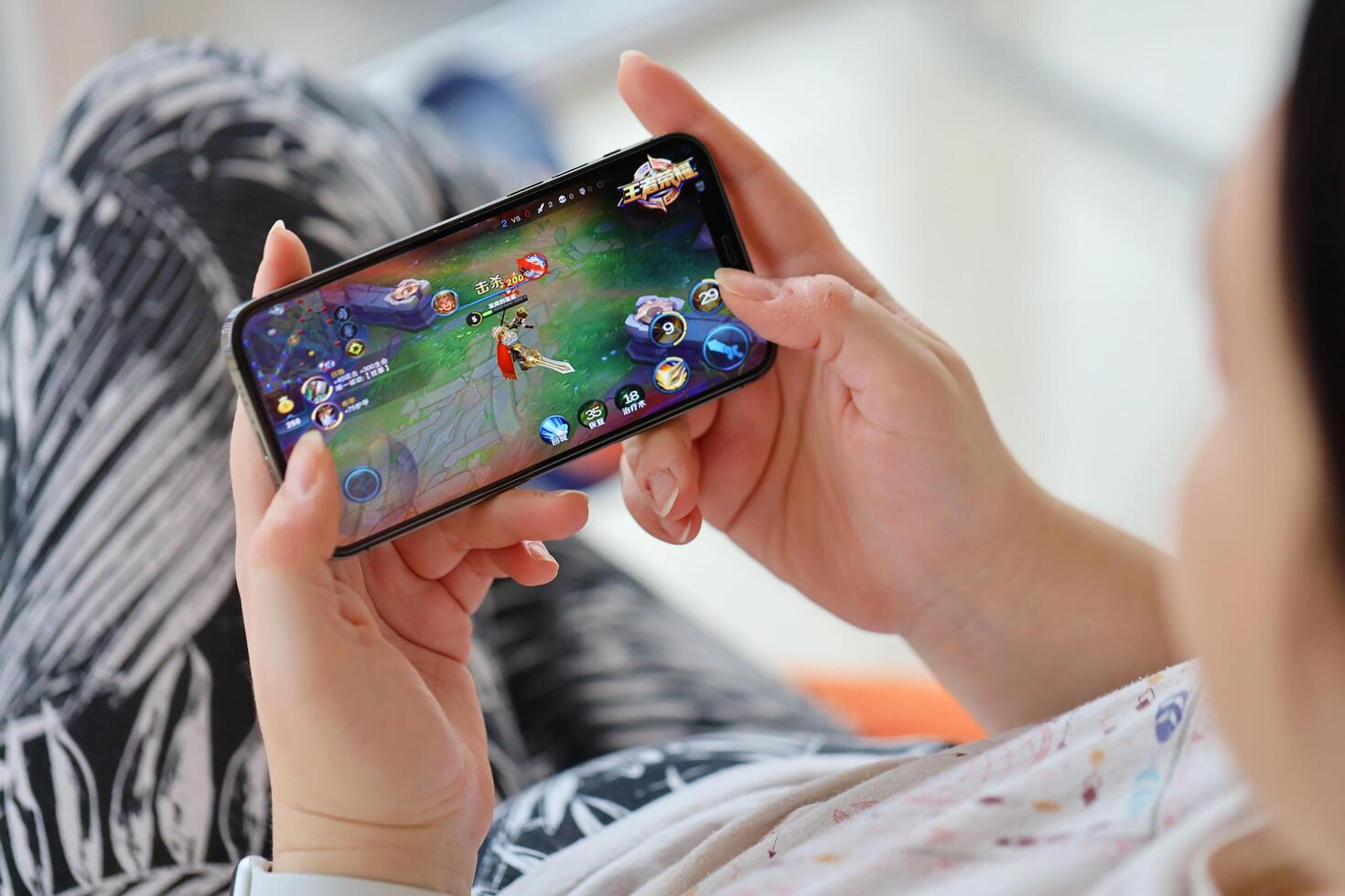 Honor of Kings mobile iOS game on iPhone 15 smartphone screen in female hands during mobile gameplay photo