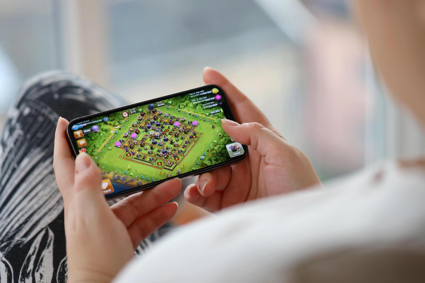 Clash of Clans mobile iOS game on iPhone 15 smartphone screen in female hands during mobile gameplay photo