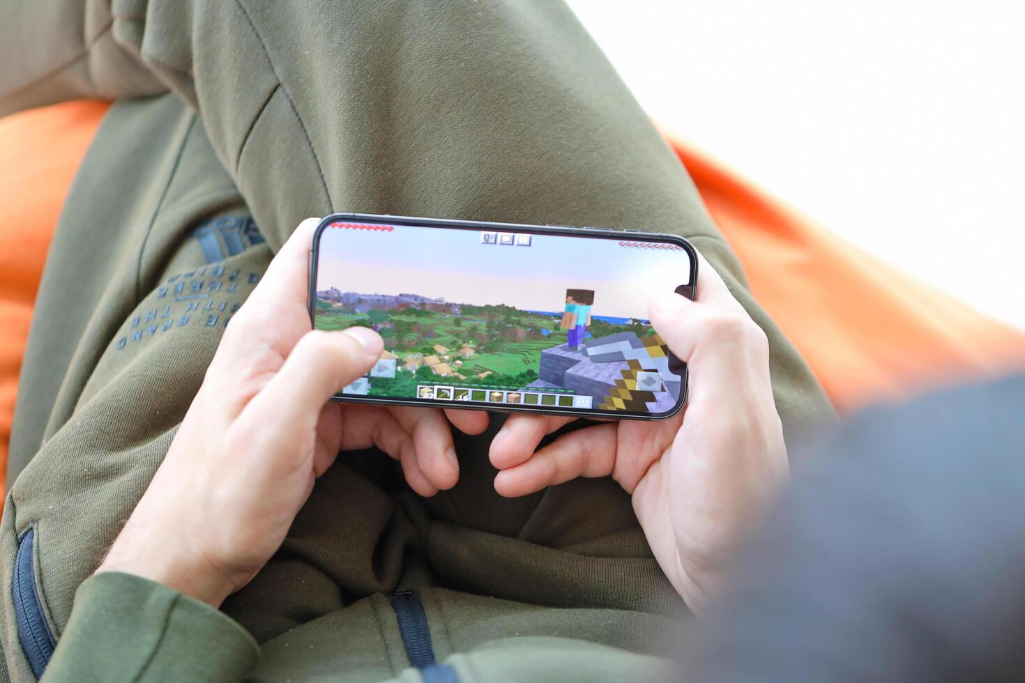 Minecraft mobile iOS game on iPhone 15 smartphone screen in male hands during mobile gameplay photo