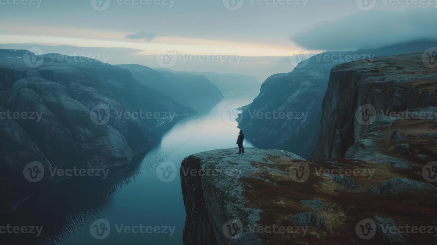 A person standing at the edge of a cliff, overlooking a majestic landscape photo
