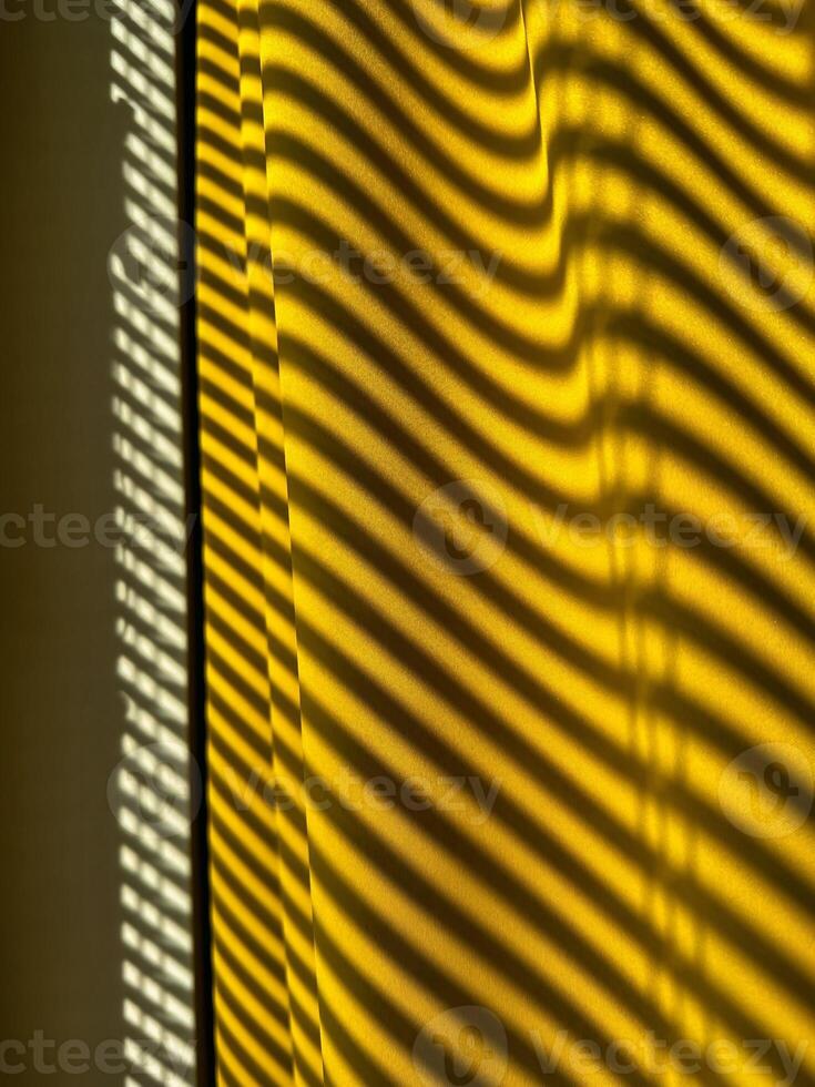 Yellow curtains with beautiful shade from blinds on a sunny day. Abstract background. photo