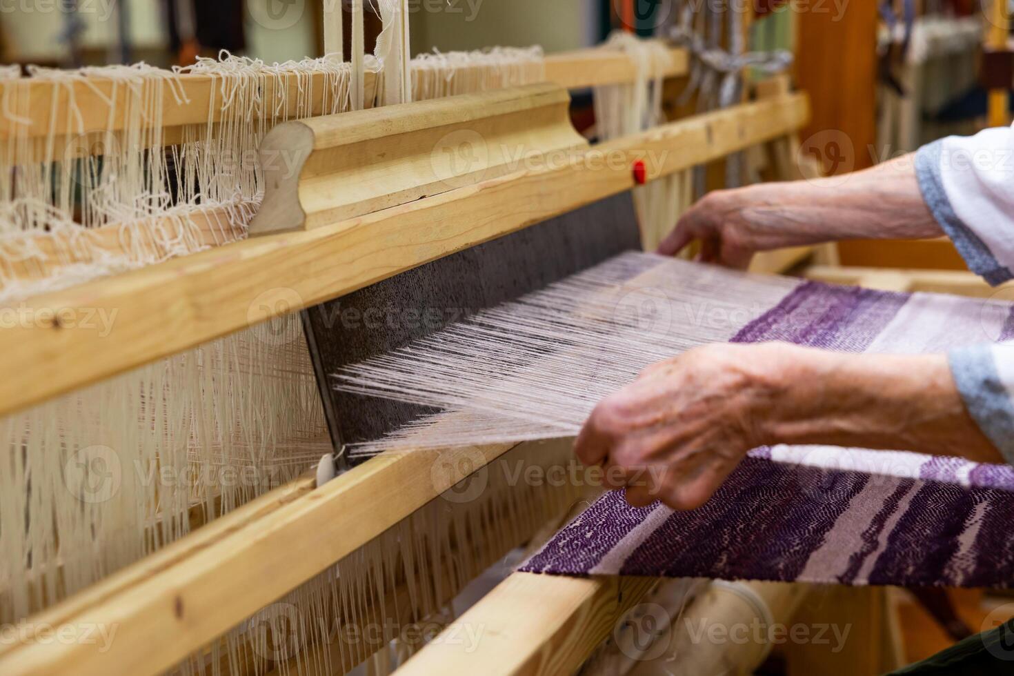 Woman is warping a wooden handloom Hands holding a heddle hook and threading the table loom Weaving tools photo