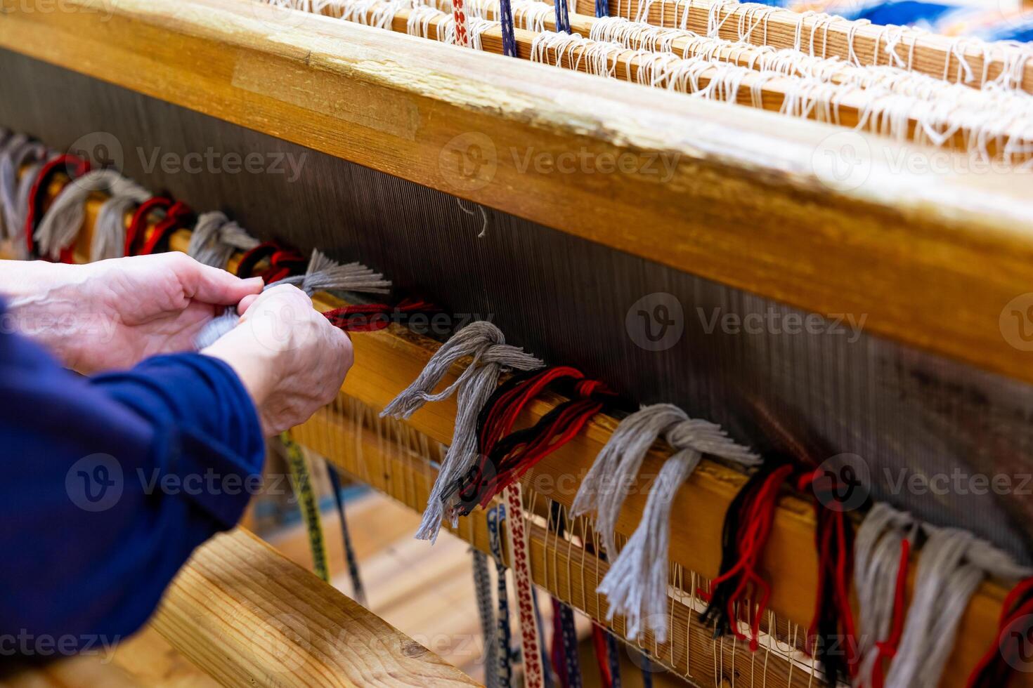 Woman is warping a wooden handloom Hands holding a heddle hook and threading the table loom Weaving tools photo