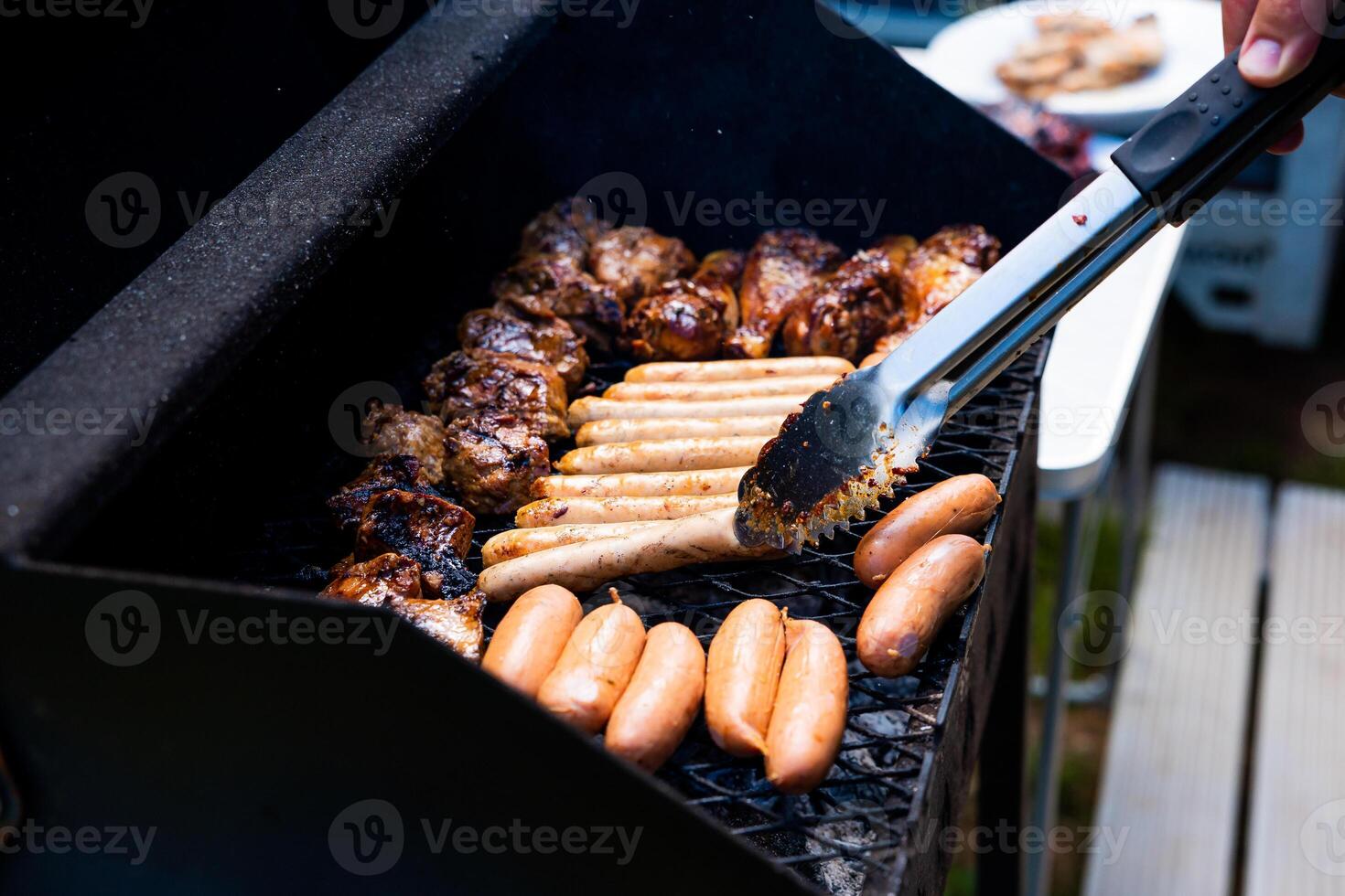 A man grills meat and sausages in the yard of a house photo