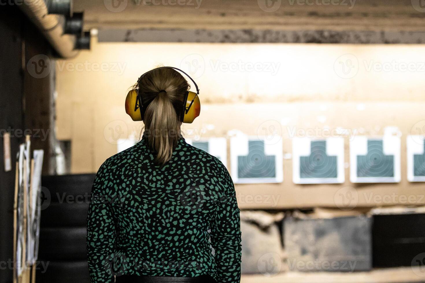 shooter in focus at a decrepit indoor range with bullet ridden targets photo
