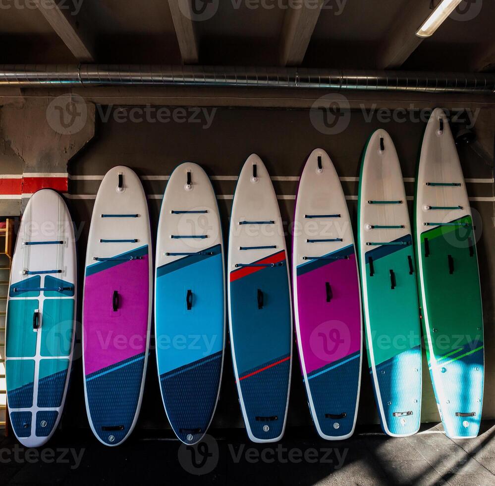 Colorful inflatable stand up paddle boards SUP by the wall Surfing and sup boarding equipment close up photo