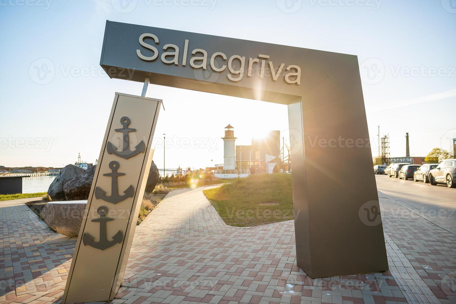 Welcoming entrance to Salacgriva in Latvia with a decorative anchor sign and lighthouse in the background photo