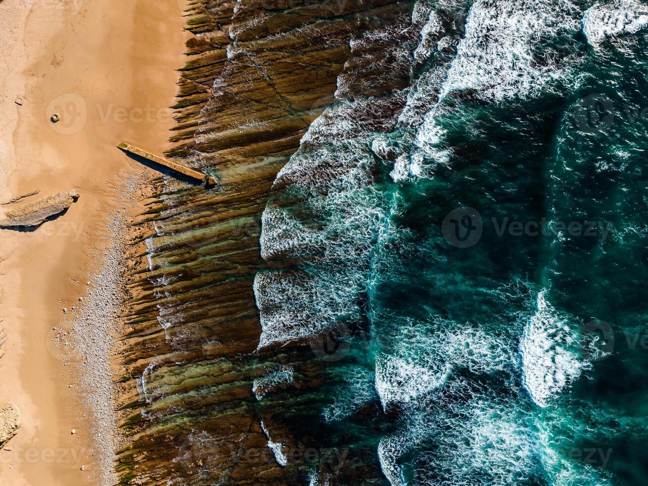 Aerial view of rocky beach with waves and clear ocean water. Drone top view photo
