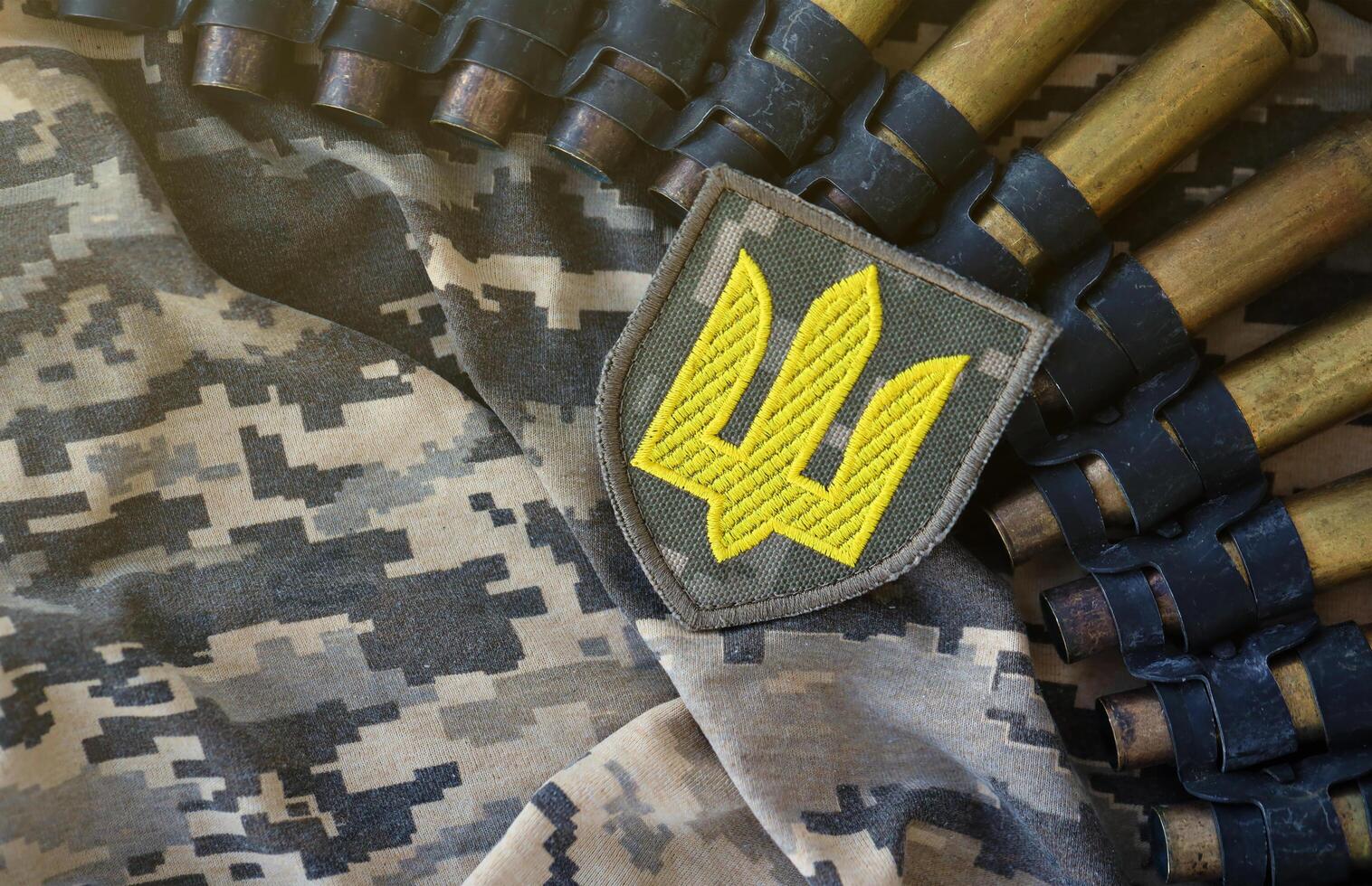 Ukrainian army symbol on machine gun belt lies on ukrainian pixeled military camouflage photo