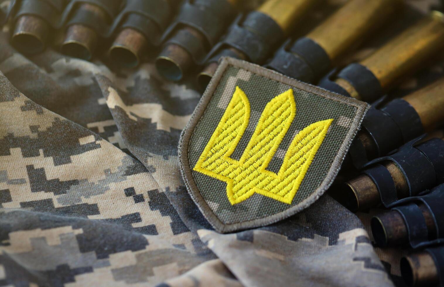 Ukrainian army symbol on machine gun belt lies on ukrainian pixeled military camouflage photo