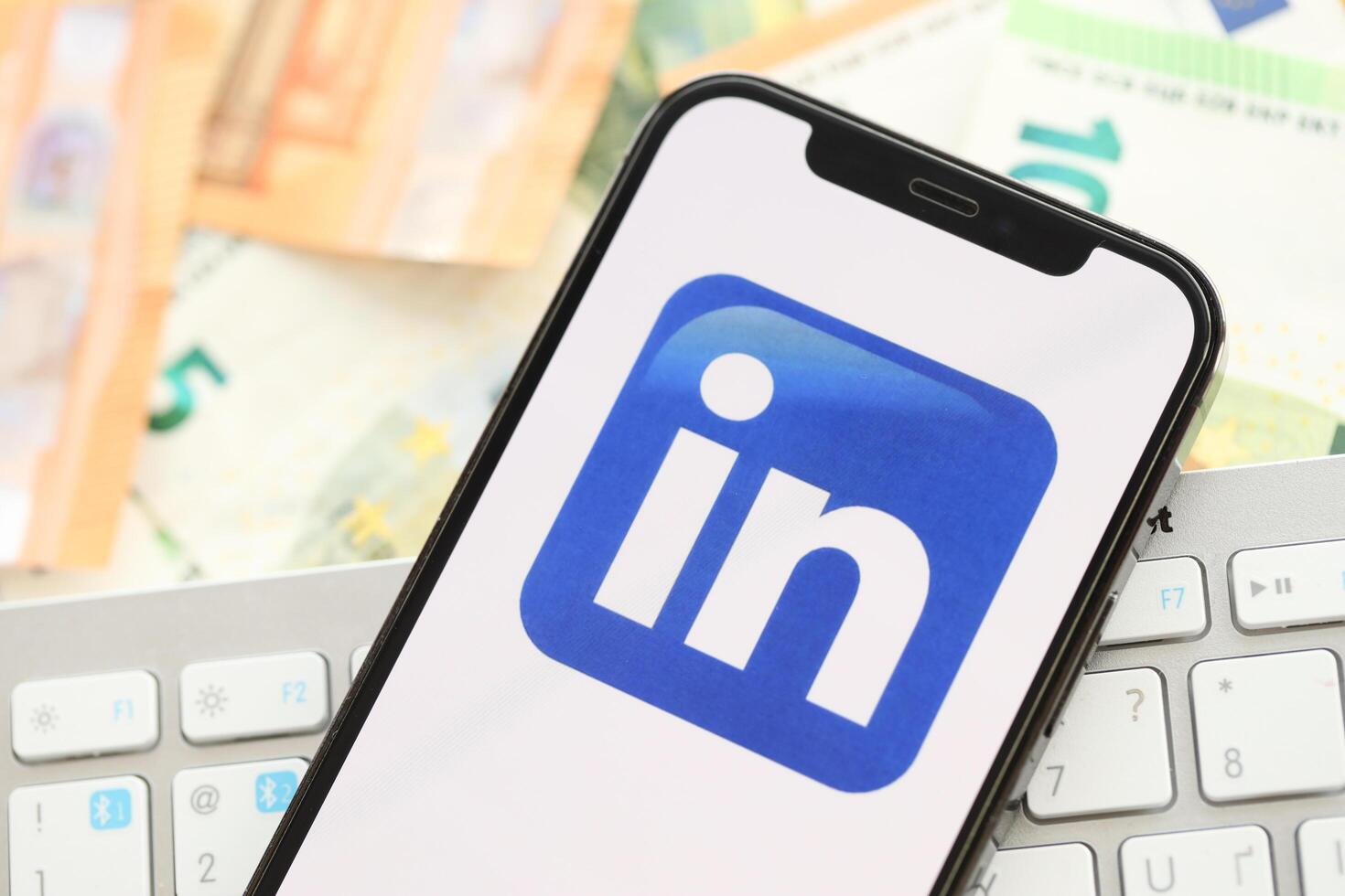 KYIV, UKRAINE - APRIL 1, 2024 LinkedIn icon on smartphone screen on many euro money bills photo
