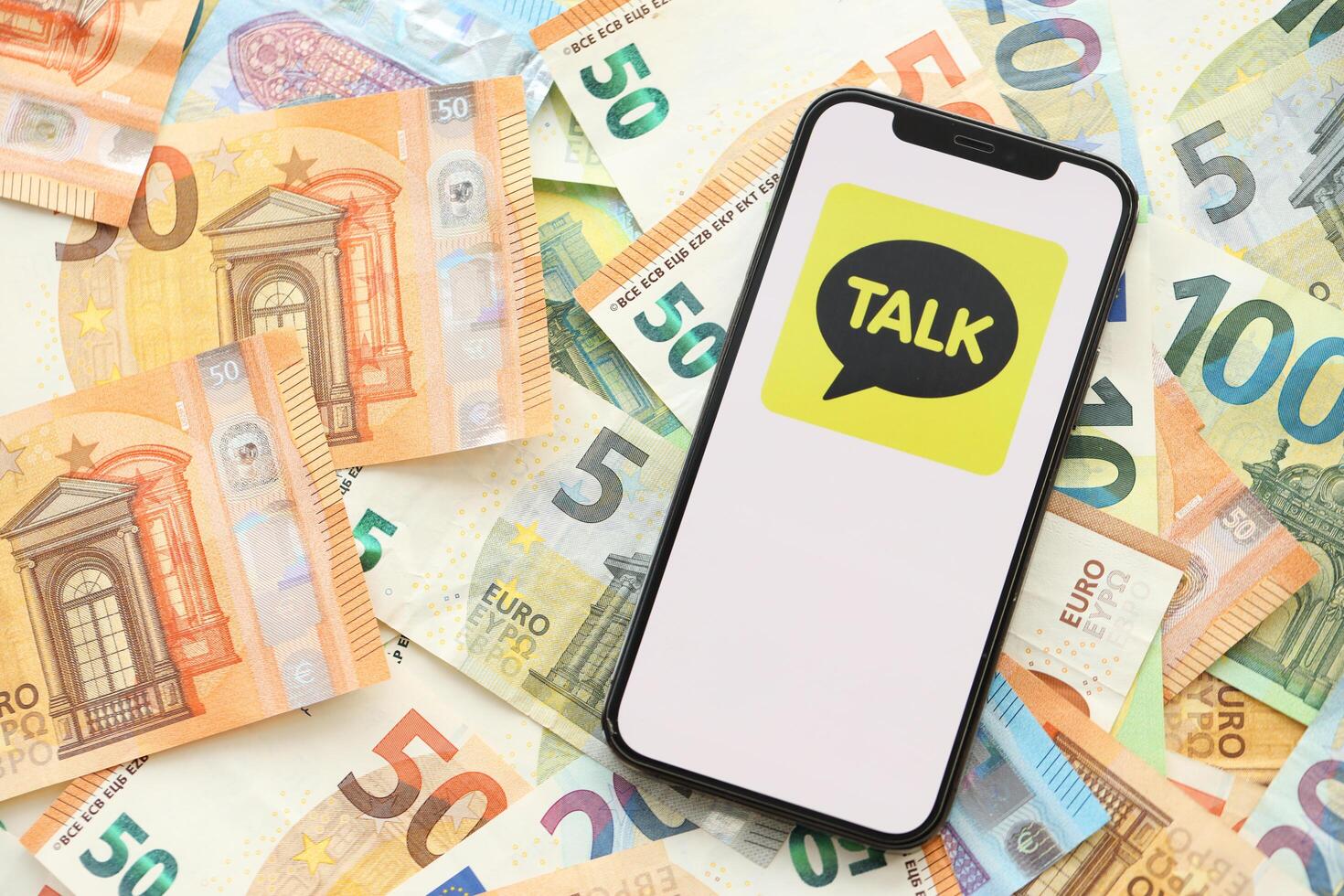 KYIV, UKRAINE - APRIL 1, 2024 KakaoTalk messenger icon on smartphone screen on many euro money bills photo