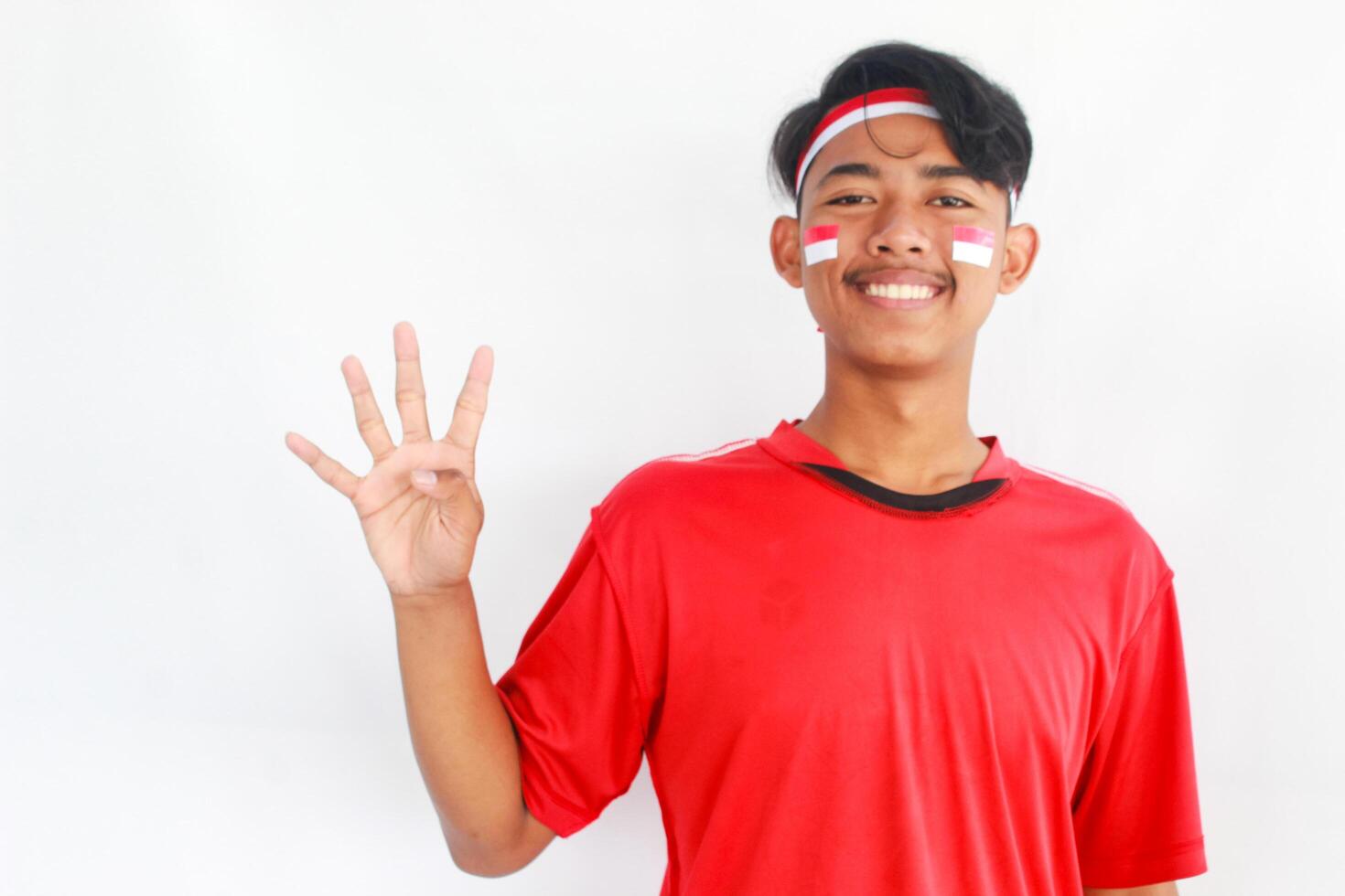 A confident young Asian man makes a number sign on an isolated white background. wearing a red shirt. Indonesian Independence day photo