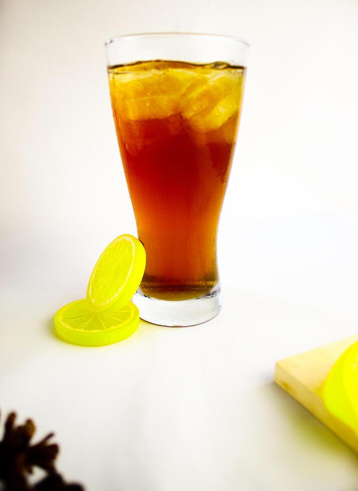 Iced tea with lemon and ice in a tall glass on a white background. The concept of a refreshing drink or lemonade on a hot summer day. Front view and copy space. photo