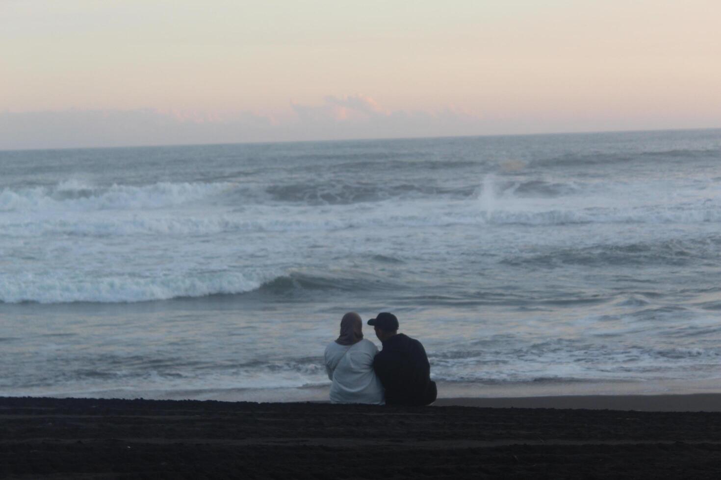 2 people were reading the Koran in the afternoon while looking at the beauty of the coast and sea photo