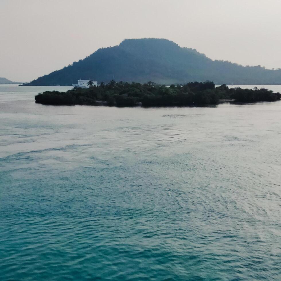 the view of an island in the middle of the ocean with a beautiful sky decorated photo